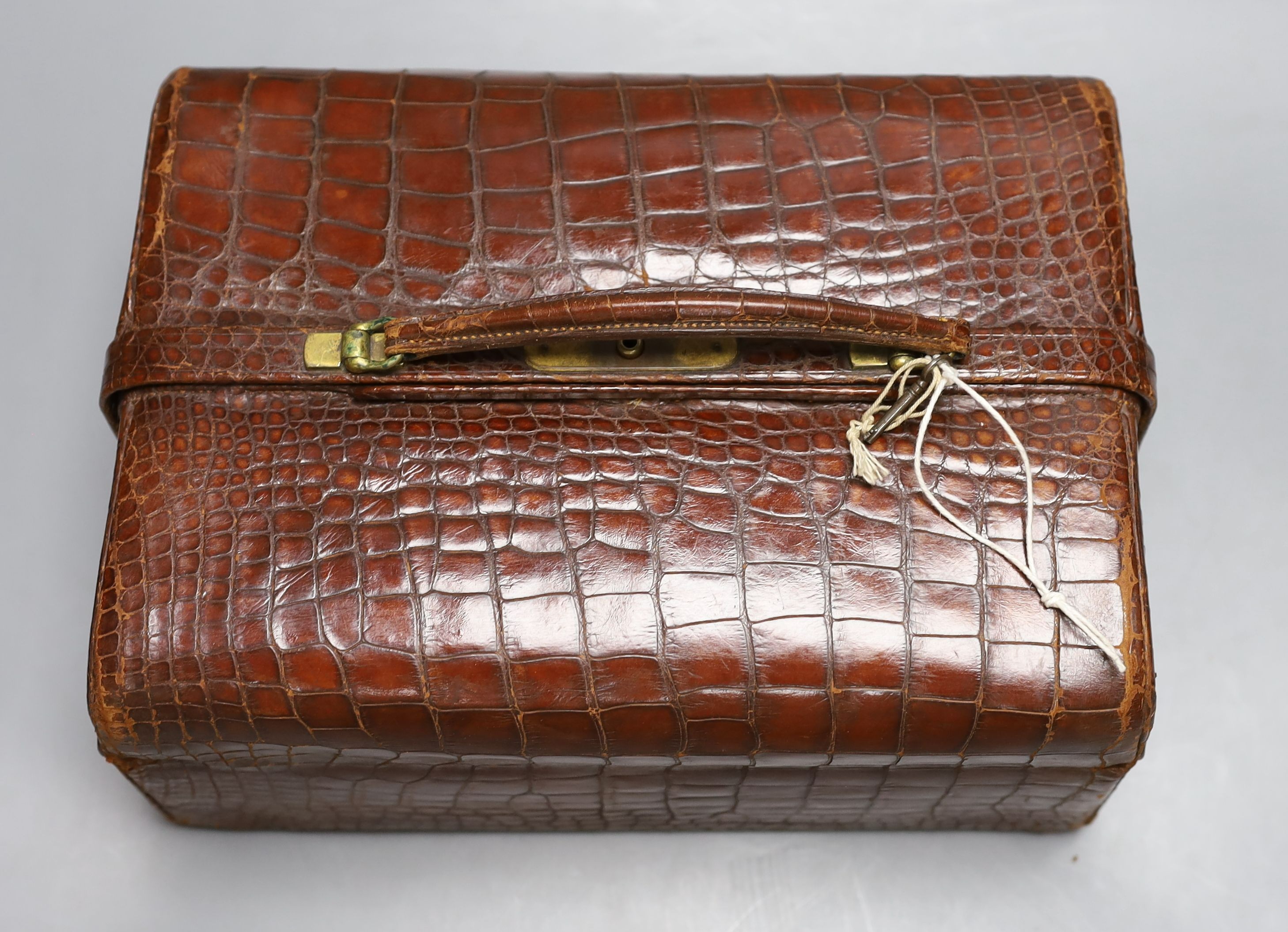 An early 20th century crocodile three tier travelling jewellery bag with key (lock a.f.) - 30cm long